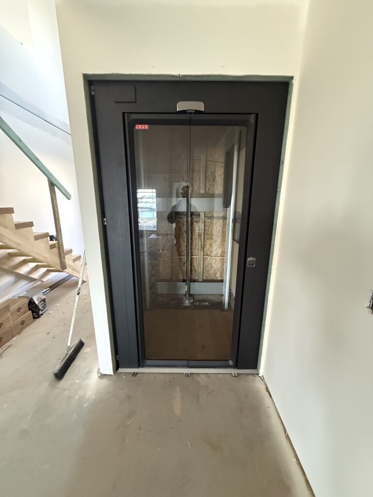 Servicing 1 Black enclosed home lift installed beside the stairs of a two-storey Kiama Heights home