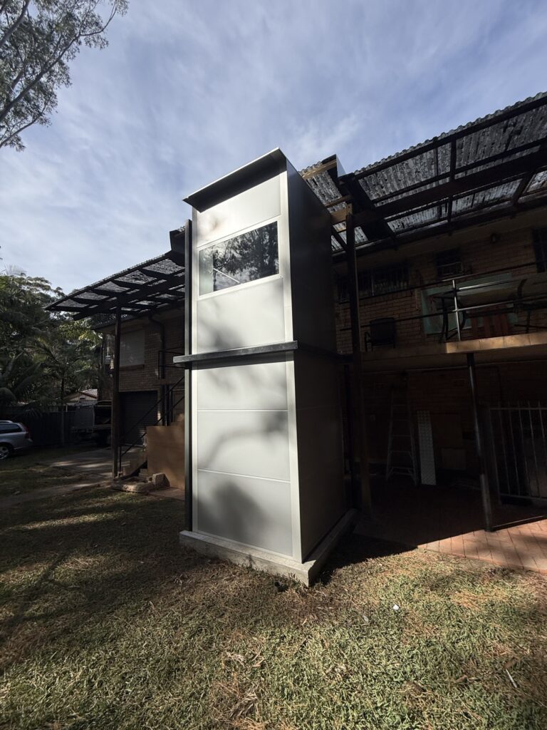 Outdoor home lift shaft installed against the exterior of a two-storey house